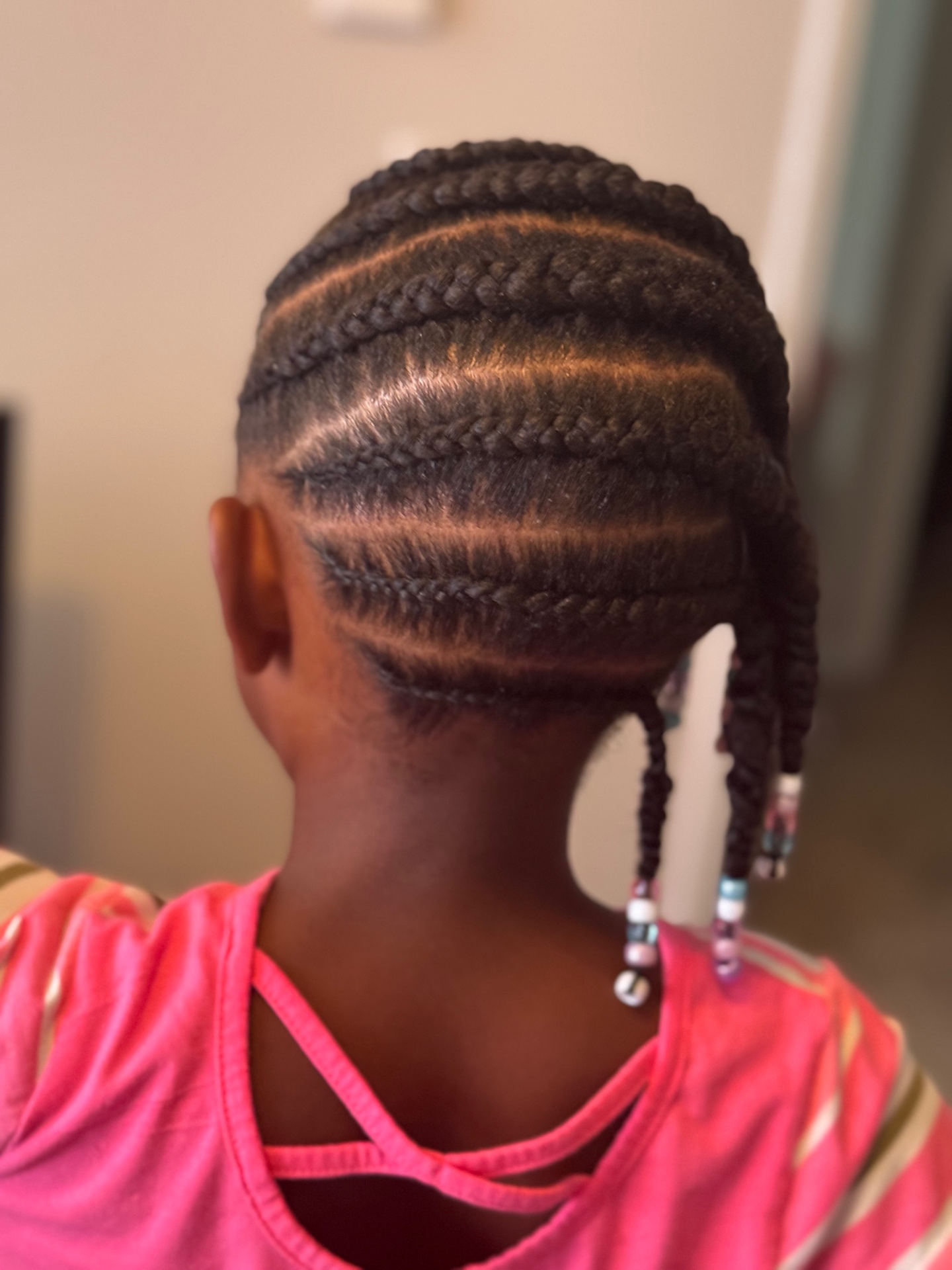 Child wearing cornrows finished with beads